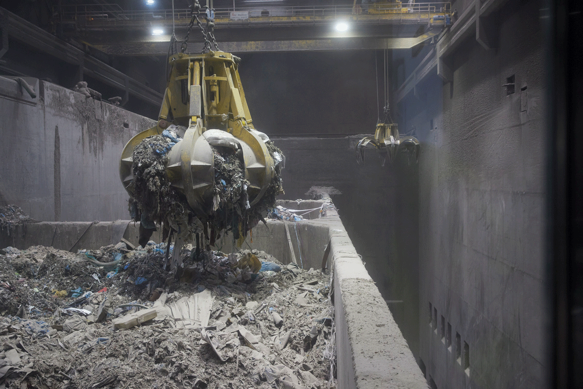 A gripper transports paper material over a collection container and feeds it into the closed production cycle