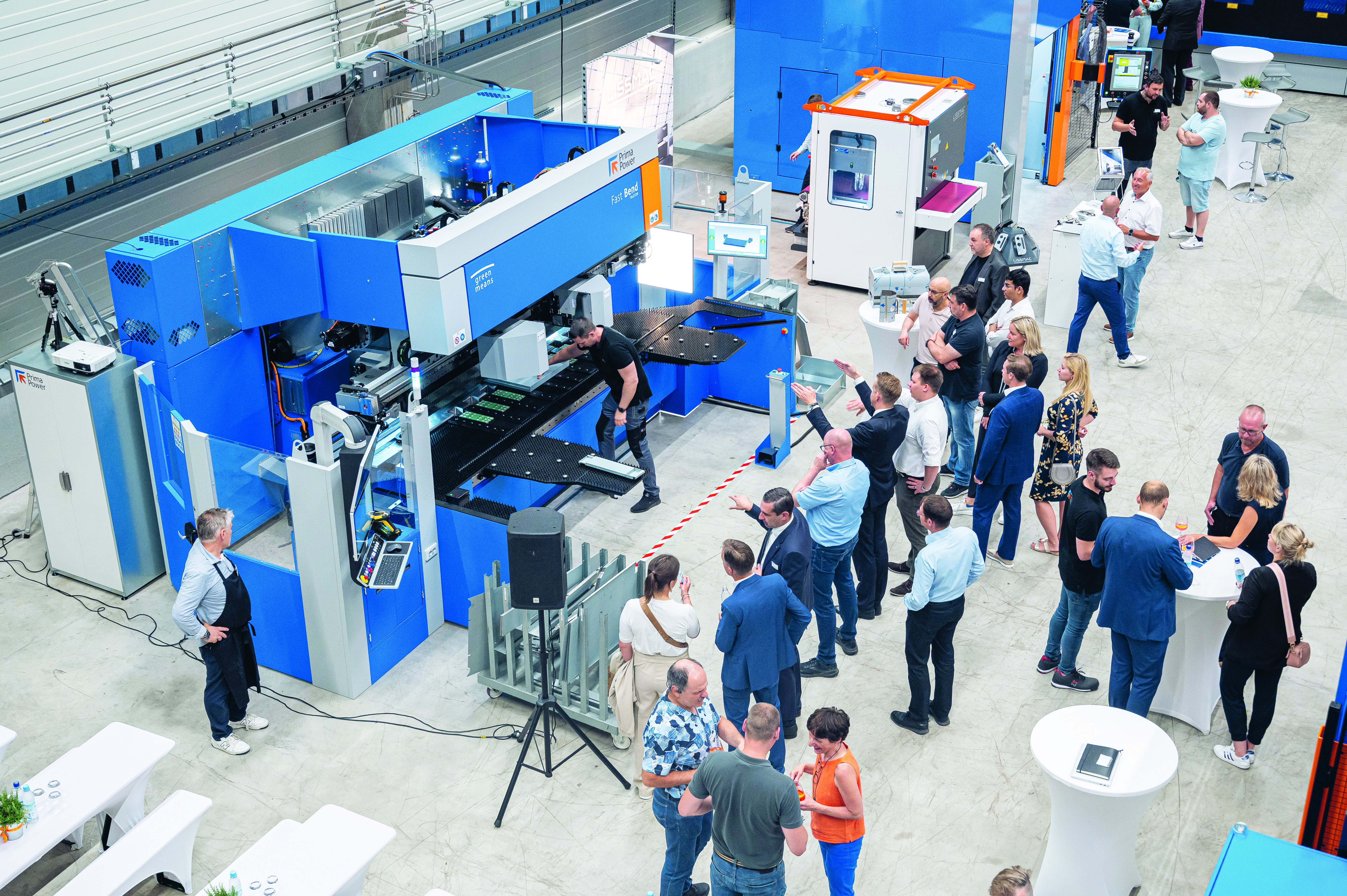 Látogatók gyűlnek össze egy Prima Power kiállítási standnál egy ipari eseményen, ahol automatizált gyártási megoldásokról tárgyalnak